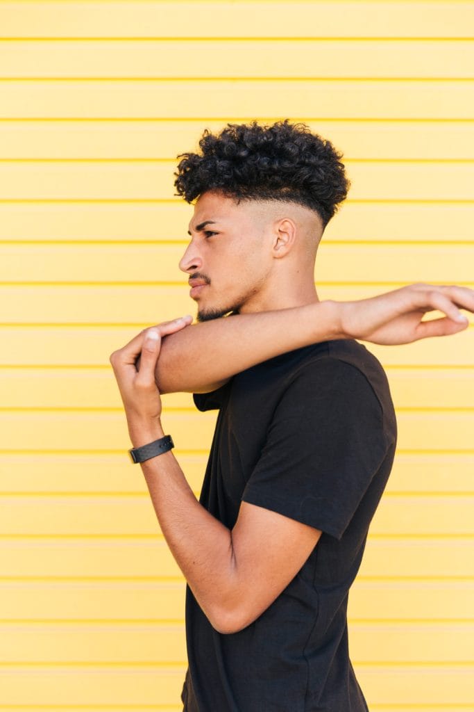 10 Best Ideas High Taper Fade Haircut For men 2 A man with curly hair styled in a high taper fade, highlighting the sharp contrast between the tapered sides and the voluminous curls on top.